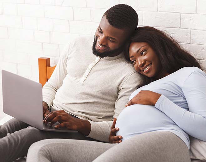 pregnant couple looking at laptop computer